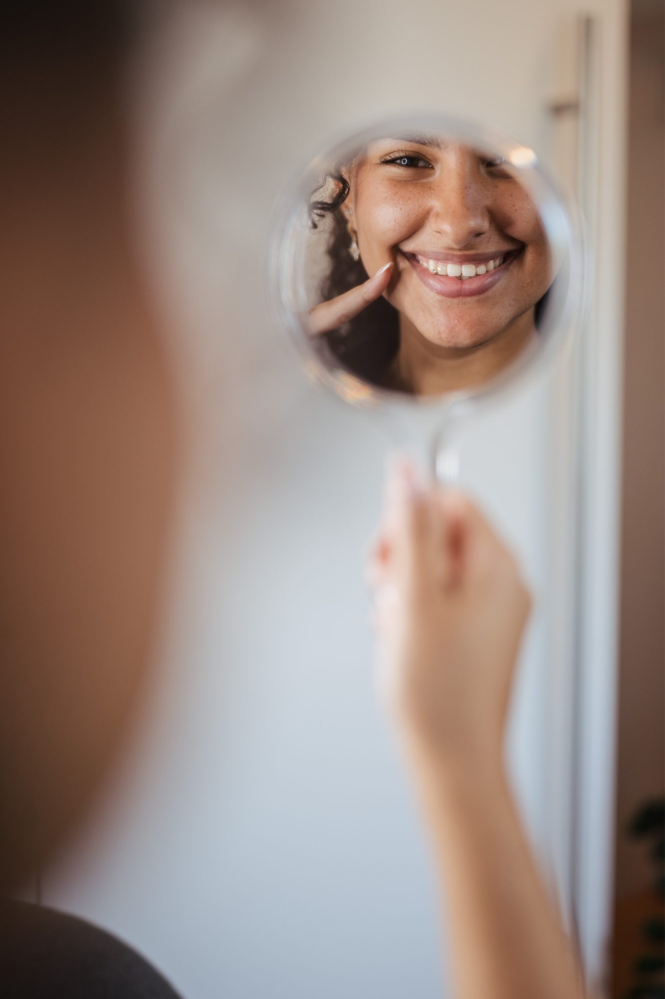 Eine junge Frau schaut sich das Ergebnis ihrer Invisalign-Behandlung im Spiegel an.